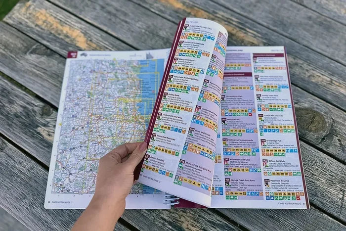 Open camps australia wide 13 guidebook with colorful index and map spread on wooden table for australia wide camping trips