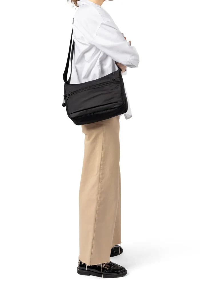 Hedgren HARPERS Small Crossbody Bag with RFID in Jungle Print, worn crossbody at the hip by a woman in a white shirt and tan trousers
