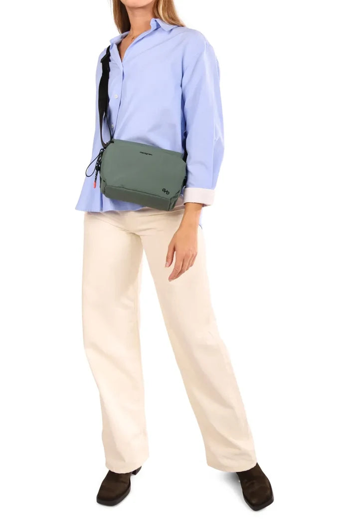 Hedgren KOSHO Medium Crossover Shoulder Bag in Black, worn crossbody at the waist over a blue shirt