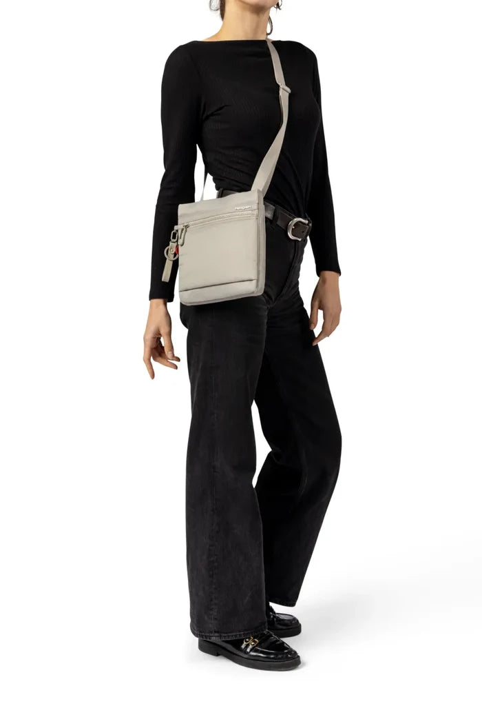 Hedgren LEONCE Small Vertical Crossbody Bag with RFID in Jungle Print, worn crossbody at the hip by a woman in a black top and dark jeans