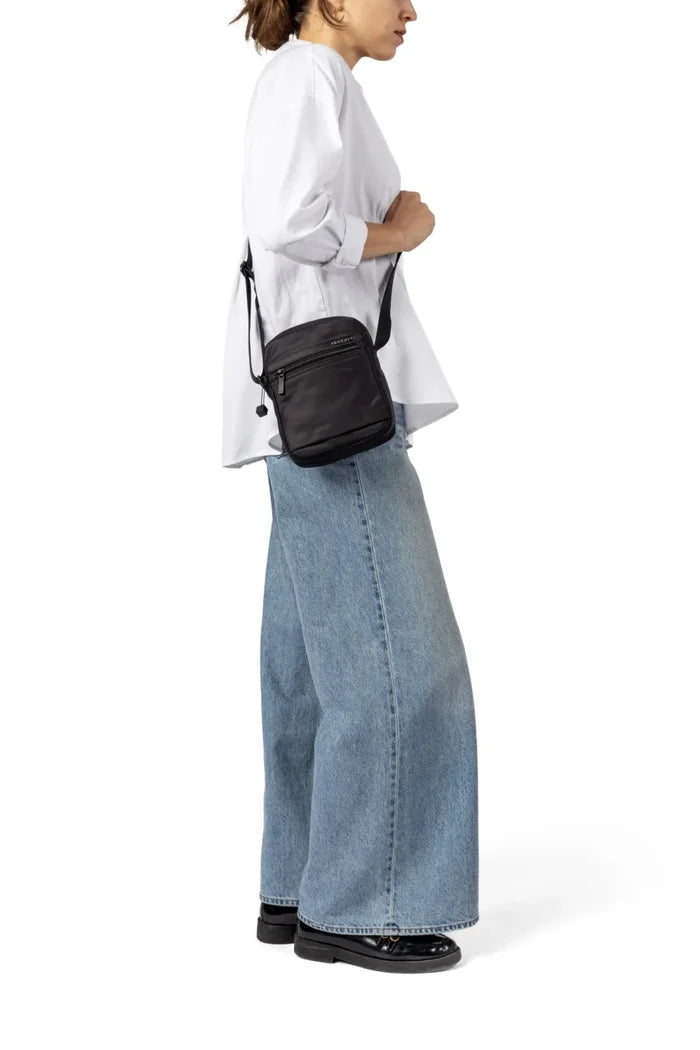 Hedgren RUSH Small Crossover Bag with RFID Pocket in Black, worn crossbody at the hip by a woman in a white shirt and wide jeans