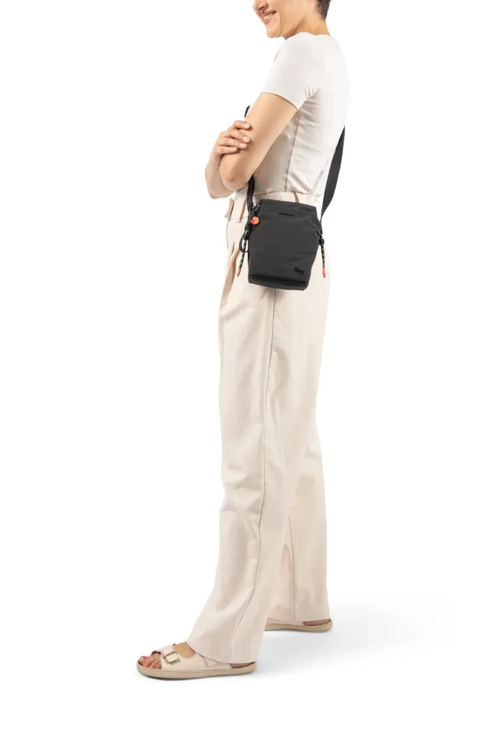 Hedgren SIPHO Phone/Bottle Bag in Black, worn crossbody at the hip by a woman in a white tee and cream trousers