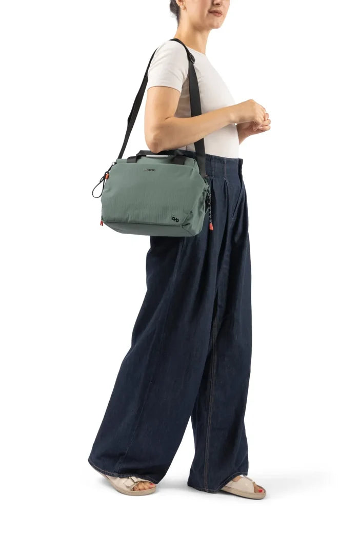 Hedgren TOMOKO Handbag in Black, carried on the shoulder by a woman in a white tee and wide denim trousers