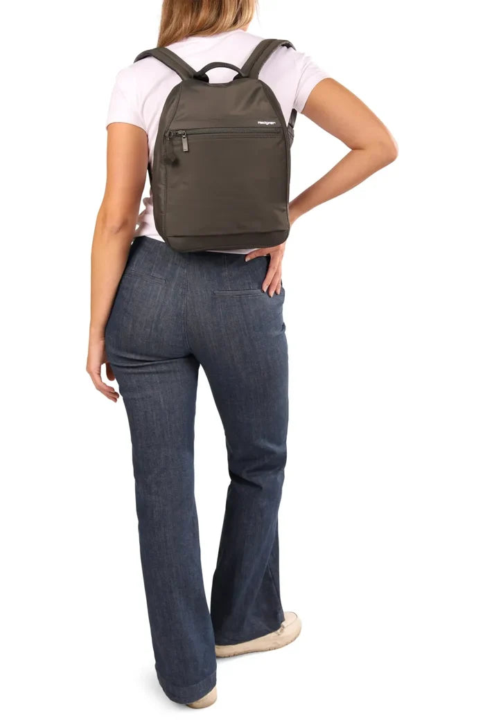 Hedgren VOGUE Large Backpack with RFID Pocket in Jean Vintage Indigo, worn on both shoulders by a woman with a hand on her hip, seen from behind